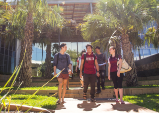 Five students smiling and walking