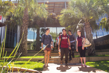 Five students smiling and walking