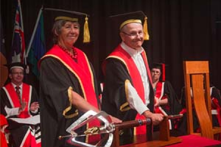 The Honourable Sally Thomas AC, handing over the university’s ceremonial mace to Mr Neil Balnaves AO symbolising the transfer of power and authority to him as new Chancellor
