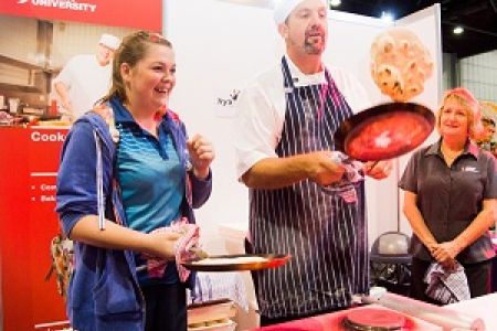 High school student Emily Elliott (left) and CDU customer service officer Tracey Worth watch CDU commercial cookery and bakery team leader Robert Schwerdt flip pita bread