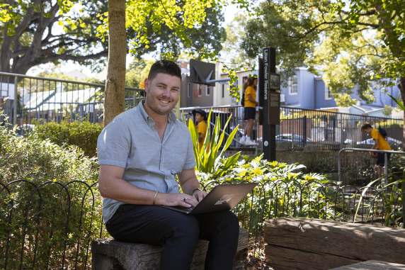 CDU student Matt North studying on his laptop in a park