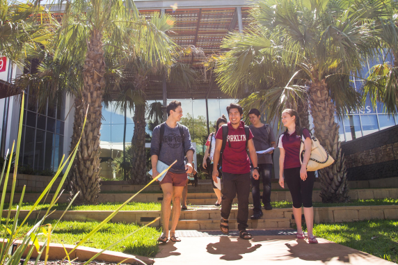 Five students smiling and walking