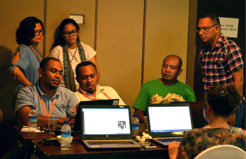 A group of people sit around a set of computers