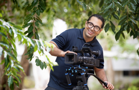 BP smiling in the garden holding a camera