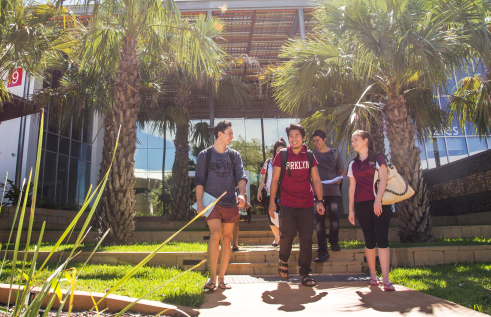 Five students smiling and walking