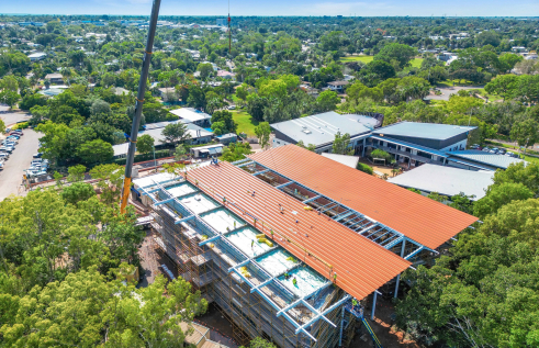 Aerial shot of building under construction with metal roof being installed.