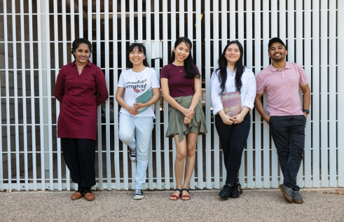 students leaning on wall outside