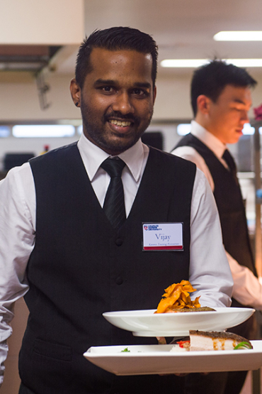 Student in training with a plate of food at Karawa Training Restaurant in Palmerston 